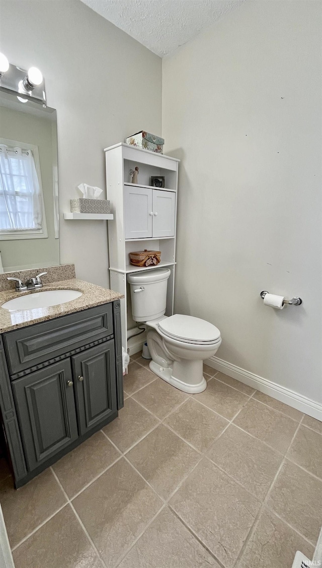 half bath featuring baseboards, toilet, tile patterned flooring, a textured ceiling, and vanity