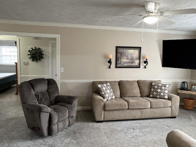 living area featuring a textured ceiling, ornamental molding, carpet flooring, and a ceiling fan