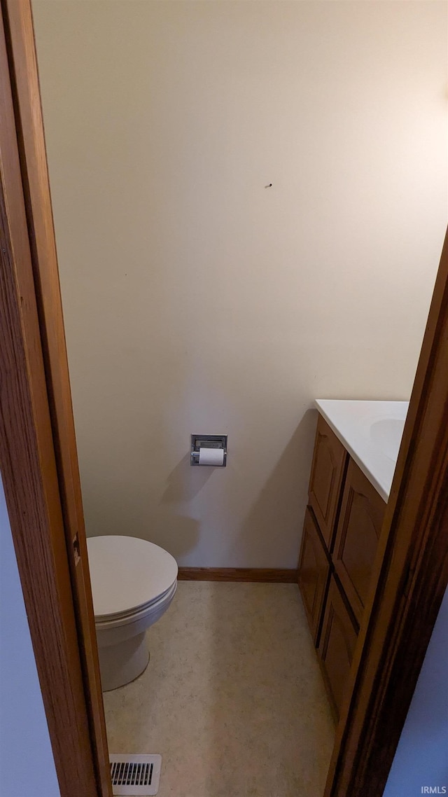 bathroom with baseboards, visible vents, vanity, and toilet