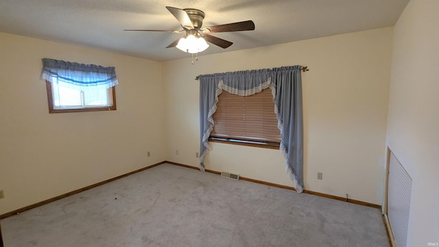 empty room with carpet floors, baseboards, visible vents, and ceiling fan