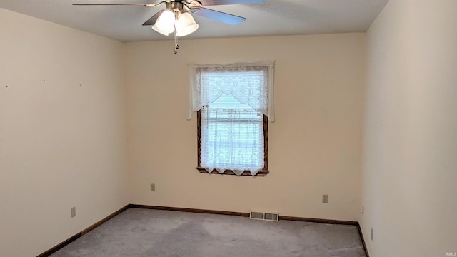 unfurnished room featuring baseboards, a ceiling fan, visible vents, and light colored carpet