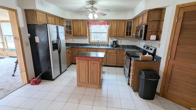 kitchen with a center island, brown cabinets, open shelves, stainless steel appliances, and a sink