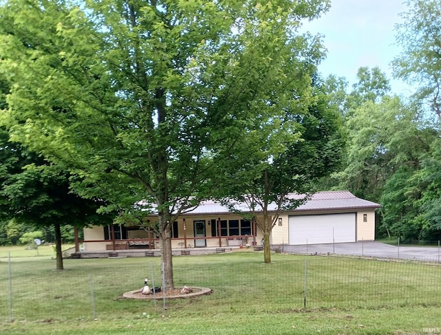 ranch-style house with metal roof, a porch, an attached garage, concrete driveway, and a front lawn