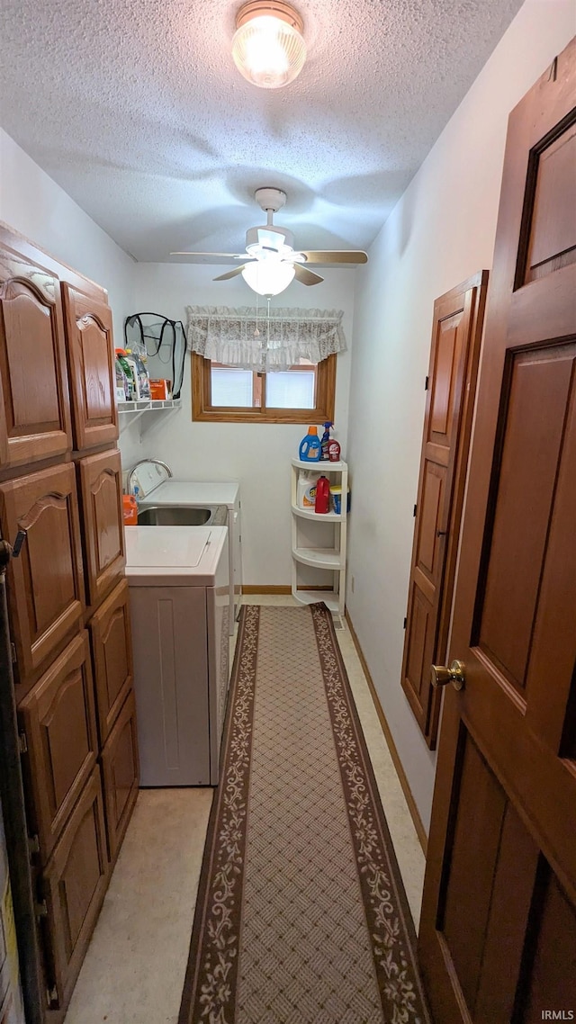 washroom featuring a textured ceiling, washer and clothes dryer, cabinet space, and a ceiling fan