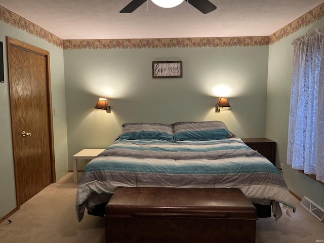 carpeted bedroom featuring a textured ceiling, visible vents, and a ceiling fan