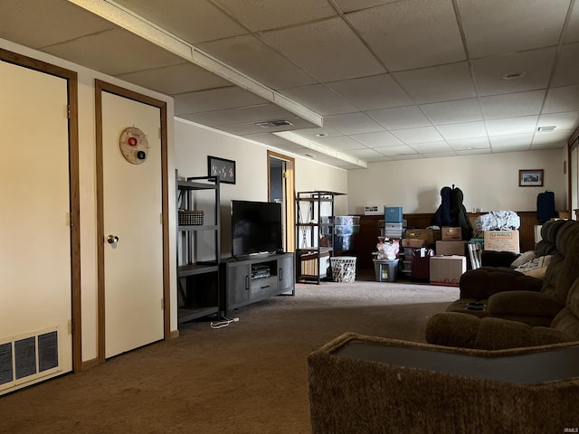 living area featuring visible vents, a drop ceiling, and carpet flooring