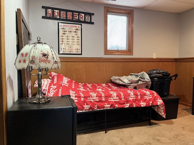 carpeted bedroom with a wainscoted wall and wood walls