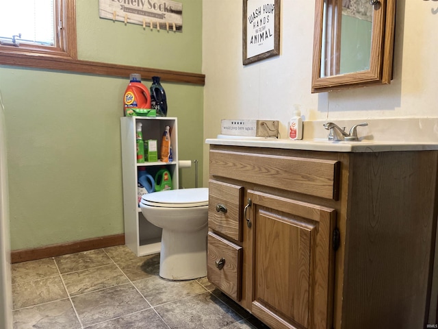 bathroom with toilet, vanity, and baseboards