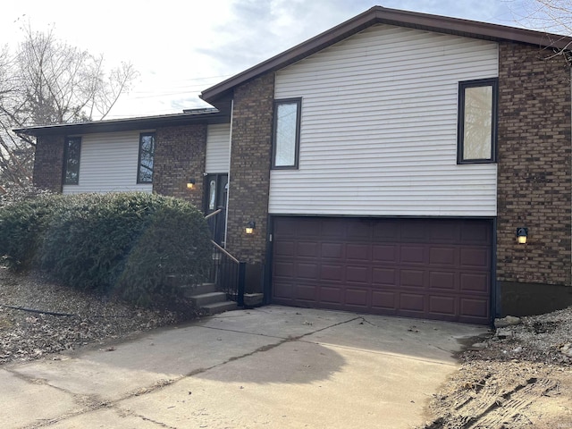 view of front of home with a garage, concrete driveway, and brick siding