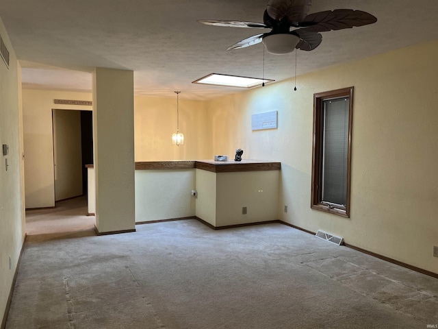 carpeted spare room with baseboards, ceiling fan, visible vents, and a textured ceiling