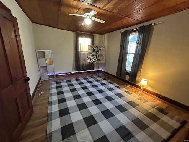 empty room featuring dark wood-style floors, wood ceiling, baseboards, and a ceiling fan