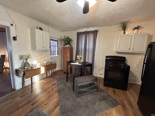 kitchen with white cabinets, ceiling fan, a textured ceiling, wood finished floors, and black appliances