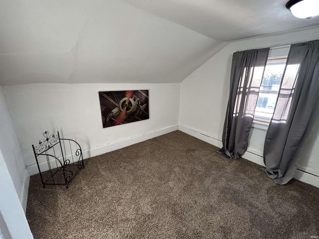 bonus room featuring dark colored carpet, vaulted ceiling, and baseboards