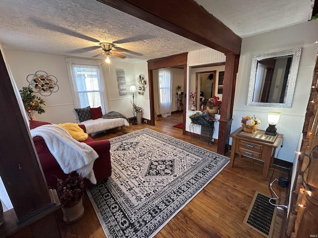 living area with visible vents, ceiling fan, a textured ceiling, and wood finished floors