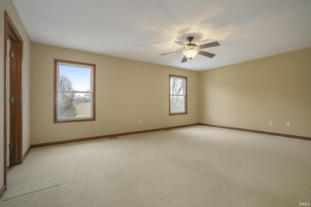 unfurnished room with light carpet, visible vents, a ceiling fan, and baseboards