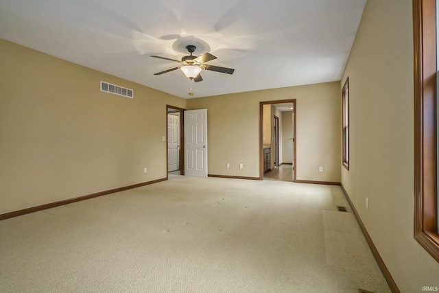 empty room featuring ceiling fan, light colored carpet, visible vents, and baseboards