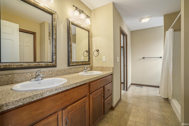 full bathroom with double vanity, a sink, and baseboards