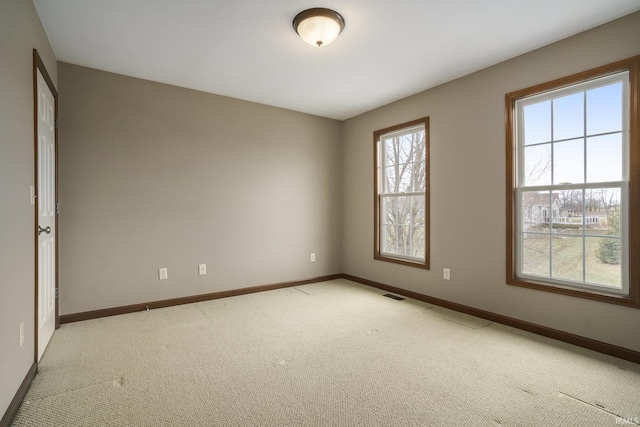 unfurnished room with light carpet, visible vents, and baseboards