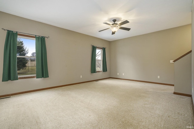 empty room featuring baseboards, ceiling fan, visible vents, and light colored carpet