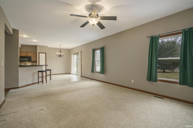 unfurnished living room with light colored carpet, visible vents, baseboards, and ceiling fan with notable chandelier