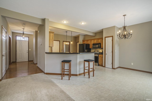 kitchen with a peninsula, baseboards, black appliances, dark countertops, and a kitchen bar