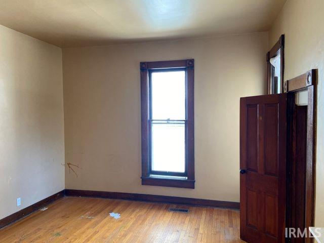 empty room with baseboards, a healthy amount of sunlight, and light wood finished floors