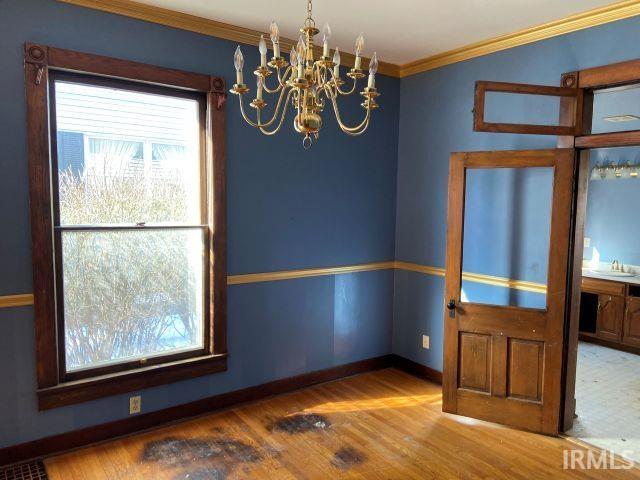 spare room featuring baseboards, a sink, wood finished floors, and crown molding