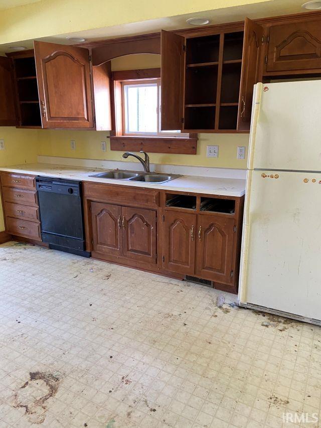 kitchen featuring black dishwasher, freestanding refrigerator, light floors, open shelves, and a sink