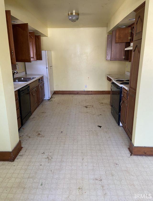 kitchen featuring a sink, baseboards, light countertops, black appliances, and light floors