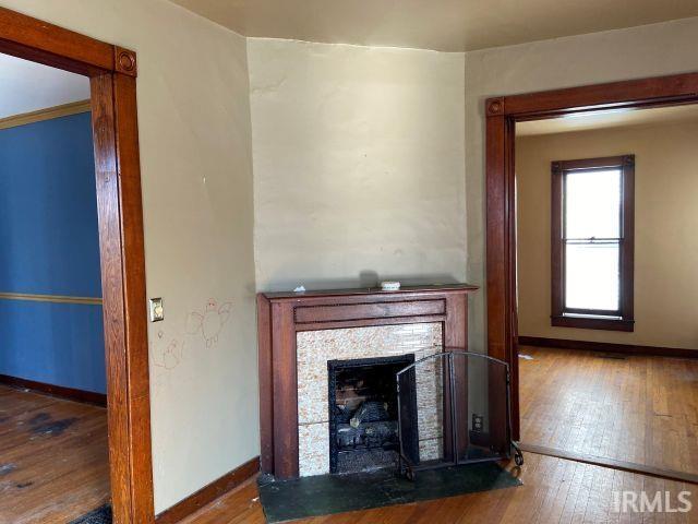 unfurnished living room with wood-type flooring, baseboards, and a fireplace with flush hearth