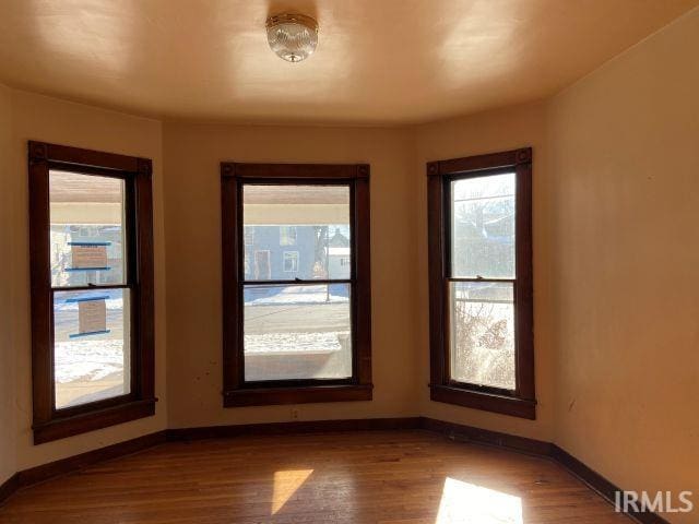 empty room featuring baseboards and dark wood finished floors