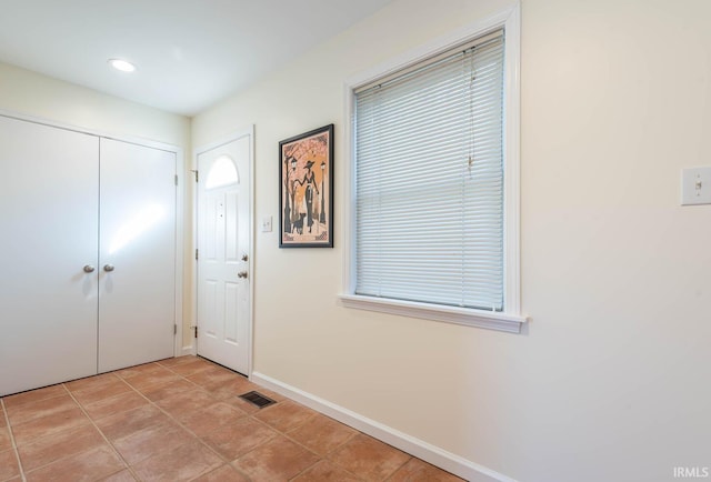 foyer entrance with light tile patterned floors, baseboards, and visible vents