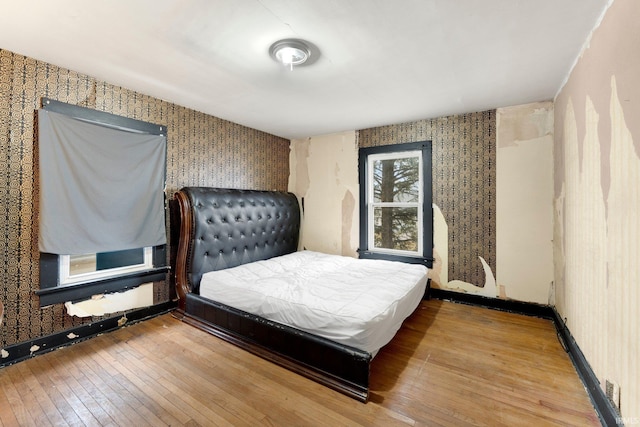 bedroom with wood-type flooring, baseboards, and wallpapered walls