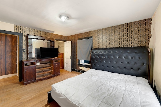 bedroom with baseboards, wood finished floors, and wallpapered walls