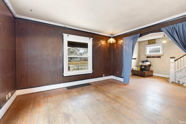 spare room featuring stairs, a wealth of natural light, visible vents, and wood finished floors