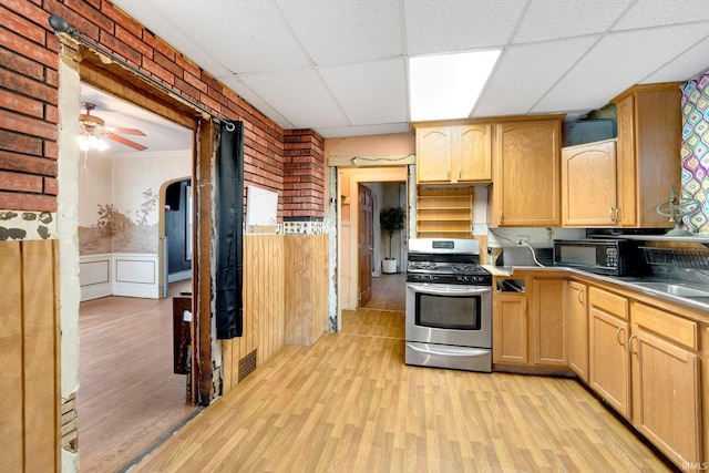 kitchen with a wainscoted wall, visible vents, light wood-style floors, light brown cabinetry, and gas stove