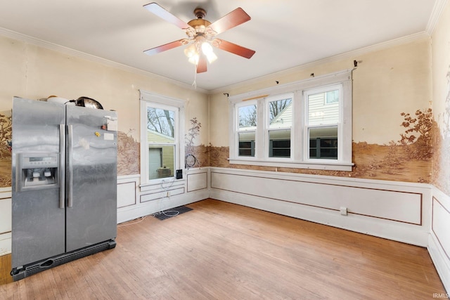 kitchen with stainless steel fridge, ornamental molding, wood finished floors, and wainscoting