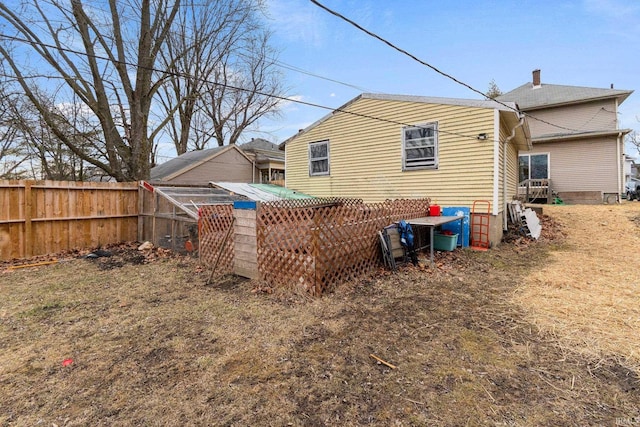 rear view of property with a chimney and fence