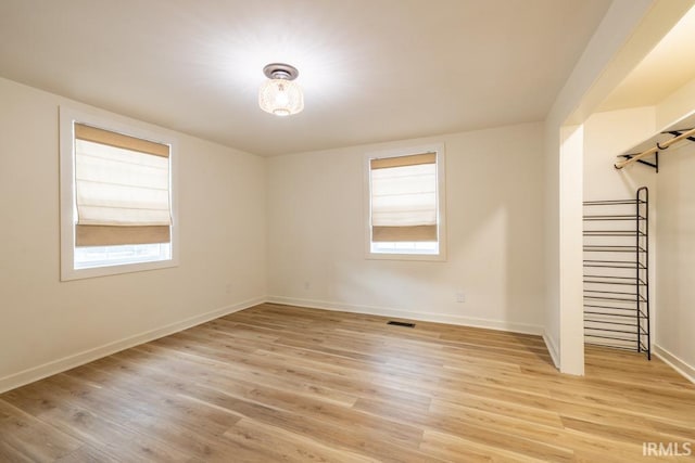 empty room with light wood finished floors and a wealth of natural light