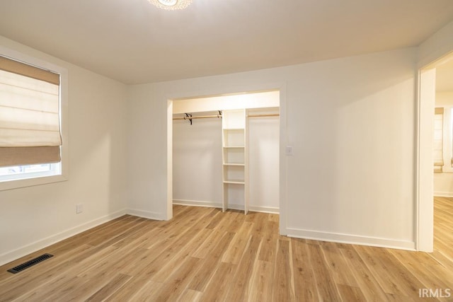 unfurnished bedroom with light wood finished floors, baseboards, visible vents, and a closet