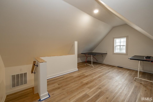 additional living space with lofted ceiling, wood finished floors, visible vents, and baseboards