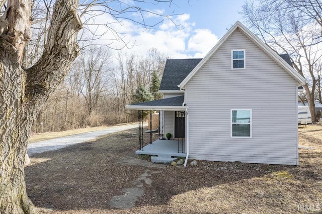 view of home's exterior with a shingled roof and covered porch