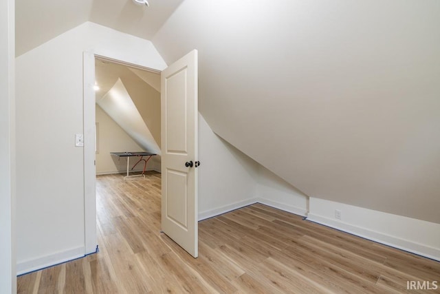 bonus room featuring light wood-type flooring, lofted ceiling, and baseboards