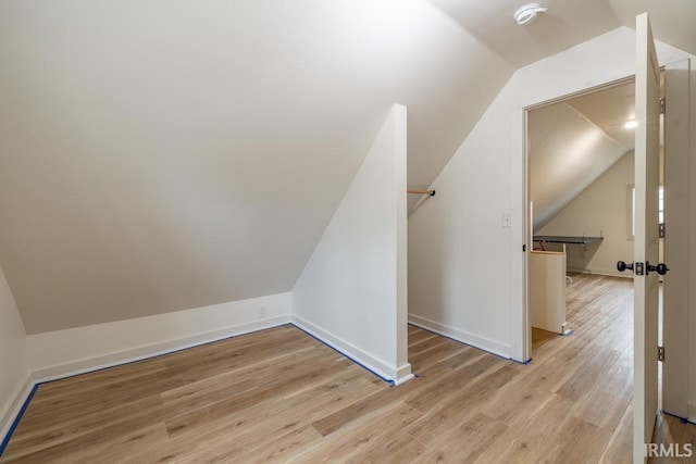 additional living space with lofted ceiling, baseboards, and wood finished floors