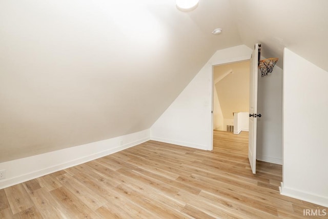 additional living space with light wood-style floors, baseboards, and vaulted ceiling