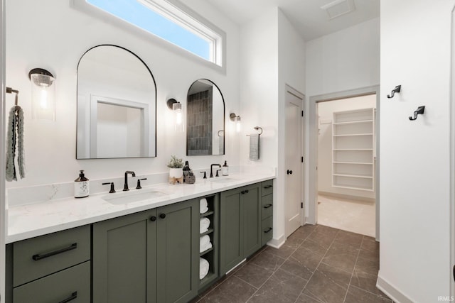 full bathroom featuring a spacious closet, double vanity, a sink, and baseboards