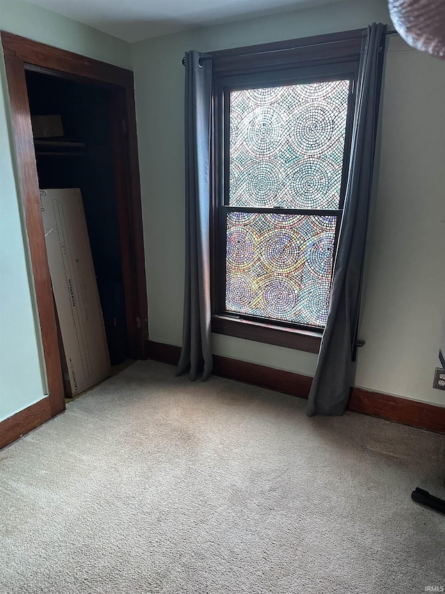 unfurnished room featuring carpet and baseboards