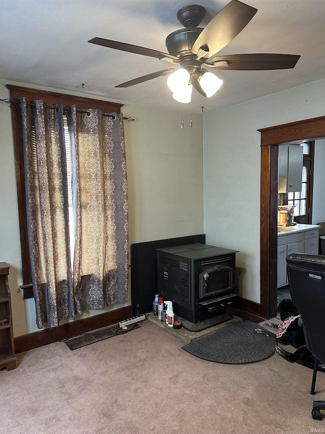 carpeted living area featuring a wood stove and baseboards