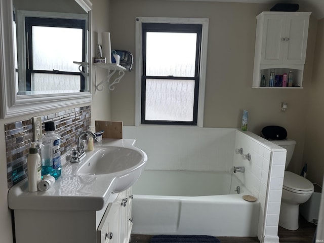 full bathroom featuring toilet, a garden tub, plenty of natural light, and vanity