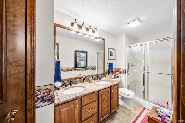 bathroom with toilet, a stall shower, a textured ceiling, and a sink